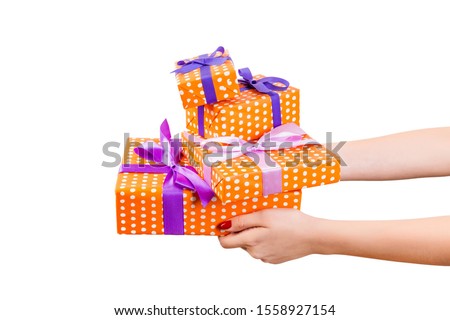 Woman hands give wrapped set of Christmas or other holiday handmade present in orange paper with purple ribbon. Isolated on white background, top view. thanksgiving Gift box concept.