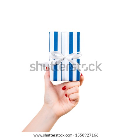 Woman hands give wrapped Christmas or other holiday handmade present in blue paper with white ribbon. Isolated on white background, top view. thanksgiving Gift box concept.