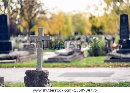 Graves at a cemetery. Cross in the foreground.