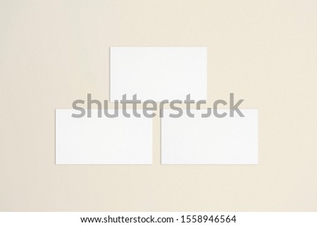 Three empty standard sized white business cards mockup on bone coloured background. Flat lay, top view. Uneven, open composition. For branding identity, logo design pitches and marketing.