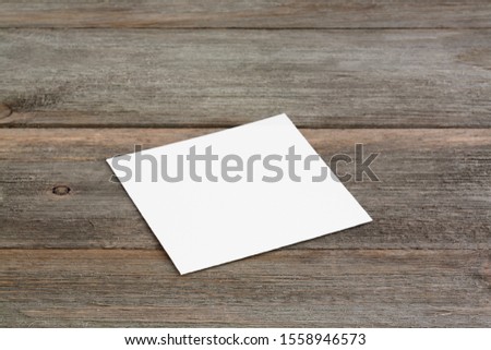 Square empty white business card mockup on brown rustic wooden background. Perspective angle with soft shadows. For branding identity, logo design pitches and marketing.