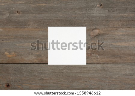 Square empty white business card mockup on brown rustic wooden background. Flat lay, top view. For branding identity, logo design pitches and marketing.
