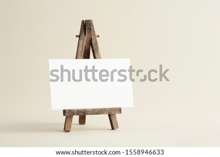 Standard sized empty white business card mockup with wooden easel on bone coloured background. For branding identity, logo design pitches and marketing.