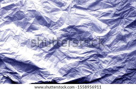 Crumpled sheet of paper with blur effect in blue tone. Abstract background and texture for design.