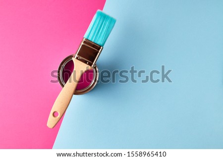 Painting brush lying on can with paint on pink and turquoise background. Minimalism, with place fo text. Royalty-Free Stock Photo #1558965410