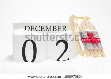Wooden calendar for December, 2 nd day of the winter month. The symbols of winter are snow and sleigh. Concept of holidays, vacation and winter fun.
