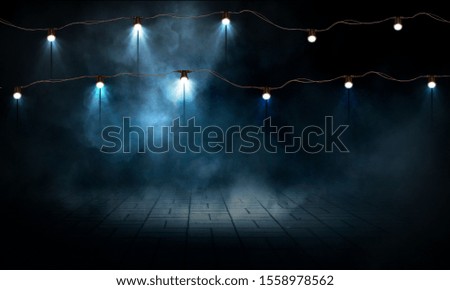 Empty background dark scene. Garland with lanterns. Dark street, wet asphalt, spotlights. Rays of neon light in the dark, smoke. Background of an empty stage show.