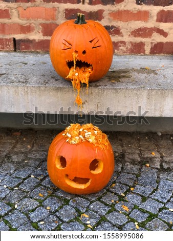 Two pumpkins, one puking on the other