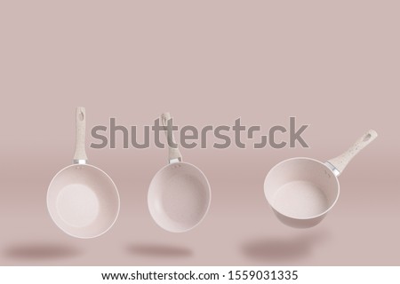 pots and pans floating above matching soft pink colored background - minimalist style household cooking objects Royalty-Free Stock Photo #1559031335