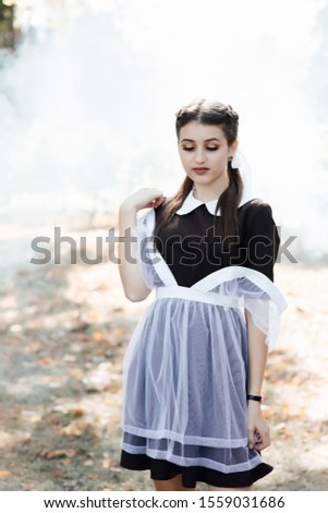 The young beautiful girl. Girl wearing in a school uniform. Outdoor photo of beautiful girl with long hair and perfect makeup. Outdoor fashion portrait of glamour lady. Сorrects straps apron
