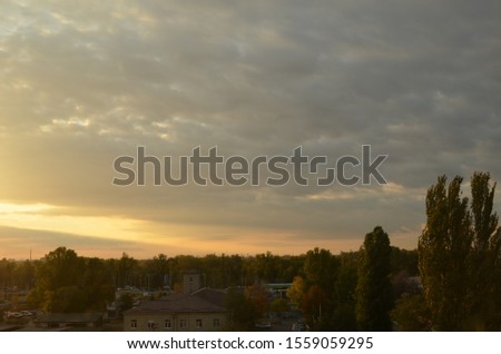 View of the dramatic sky above the sity at sunset with dark blue clouds and pink, purple and yellow flashes from the sun's rays Royalty-Free Stock Photo #1559059295