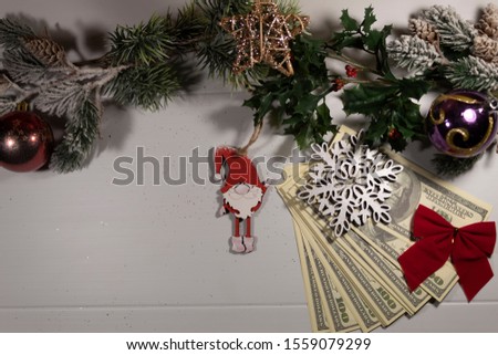 New Year. Christmas. On a white background are branches of coniferous trees, two New Year's glass balls, a star from a vine, and a dwarf. On a bundle of money is a snowflake and a red bow.