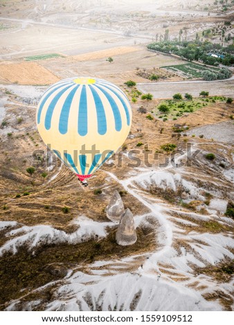 Big colorful air balloon flying over beautiful landscape in Cappadocia, Turkey. 
