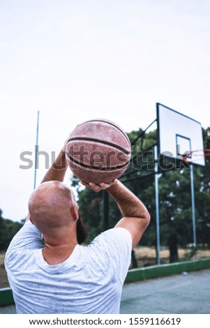 Young basketball player shooting a triple, on a street basketball court