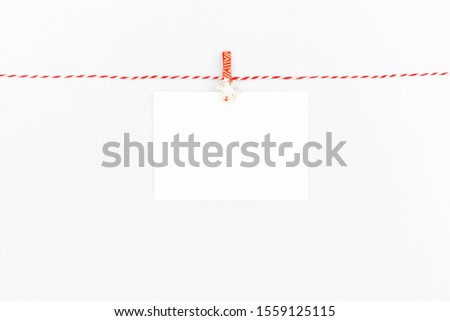 Empty Christmas card hanging on rope isolated on blue background.