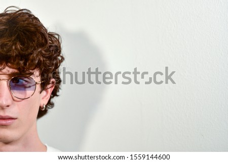 half face portrait of handsome attractive young teenager Italian model boy posing with stylish modern glasses for casual shooting. white background