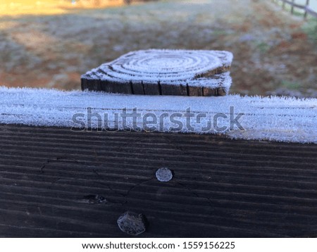 Frost covered black fence rail and post