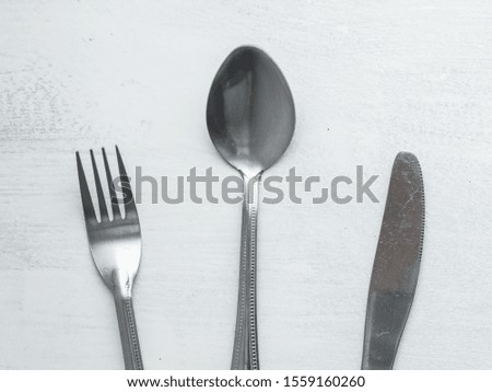 Bunch of Forks, Spoons and Knives Mixed on a Roughly Painted White Background
