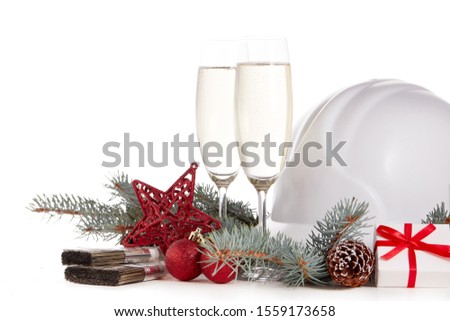 Construction hard hat, fir tree branches, two glasses with champagne, gift boxes and Christmas ornament isolated on a white background. New Year and Christmas construction background