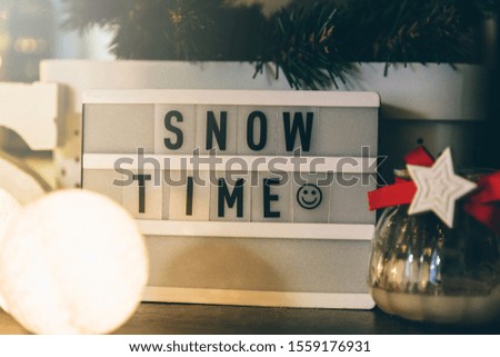 Lightbox with Snow time title. Christmas decorations, lantern, garland, balls and toys at home.