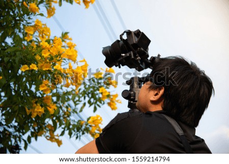 videographer man wear black shirt and dark shade taking video of flower