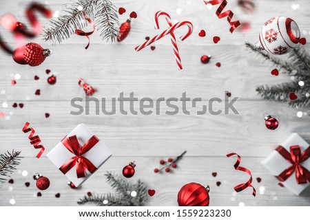 Merry Christmas and New Year background. Xmas holiday card made of flying decorations, fir branches, red balls, snowflakes, sparkles, bokeh, light on wooden background. Selective focus