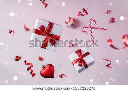 Merry Christmas and New Year background. Xmas holiday card made of flying decorations, red balls, snowflakes, sparkles, gift boxes, bokeh, light on pink background. Selective focus