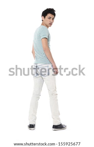 Full length young man in jeans standing back in studio