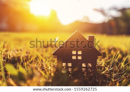 Copy space of home and life concept. Small model home on green grass with sunlight abstract background. Vintage tone filter effect color style.