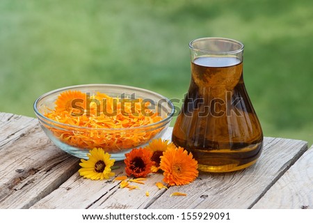 Calendula flower petals and oil extract in a glass jug 