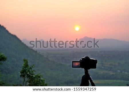 Camera on tripod and photography view camera with blurred focus landscape of sunset sunrise sun light sky cloud 
