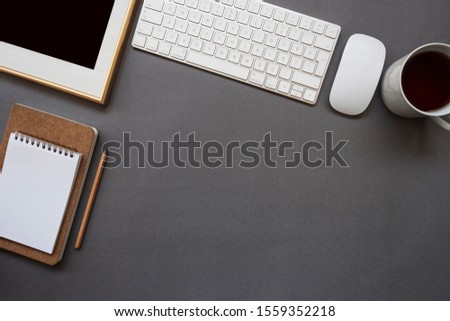 Work office desk with keyboard, mouse, coffee, notepad, pencil and frame