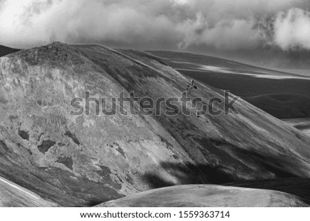 Black and white shot of a cloudy highland of Syunik region of Armenia. A mighty slope with an extinct crater in the background