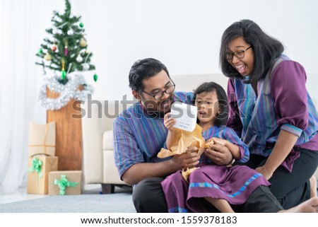 portriat of happy family with daughter open christmas gift together at home
