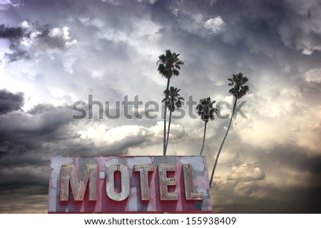 aged and worn vintage photo of stormy sky with palm trees and neon motel sign