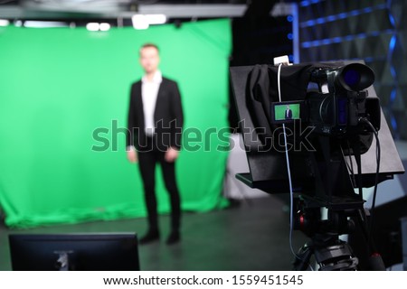 Presenter working in studio, focus on video camera