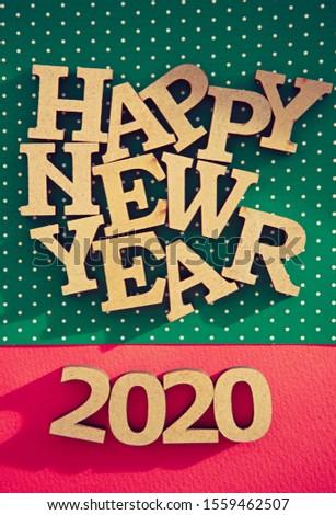 Happy New Year 2020 background.Handmade wooden letters shot on red and green holiday backdrop in flat lay style.Vertical wallpaper for winter holiday