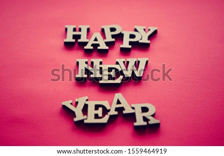 Clear red paper background for Happy New Year wallpaper.Rustic wooden letters on vibrant color backdrop.Handmade poster for winter holiday celebration party