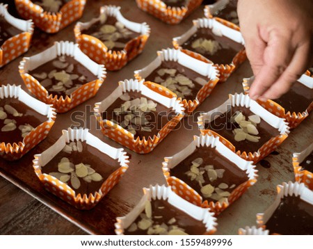 Motion blur spreading almonds sliced on homemade chocolate cupcakes on table.