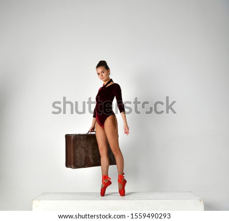 girl in a red gymnastic suit with a brown suitcase