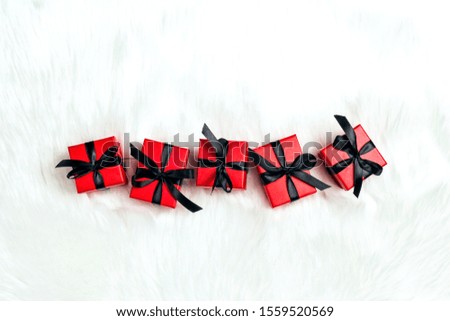 Red gift boxes with black ribbons on a white fur background. Holiday or black friday concept. Top view with copy space.
