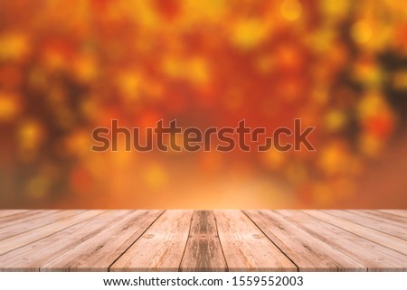 Autumn lights with wooden table and red orange background colors. Autumn concept with bokeh lights background