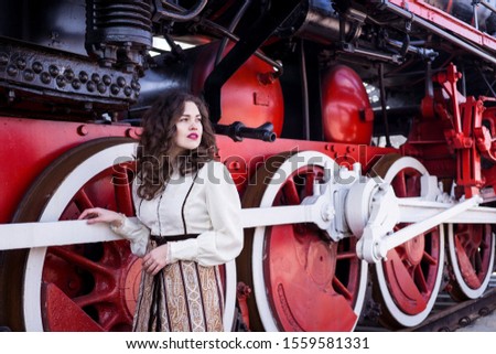 Curly gilr in retro dress near red-vlack train 