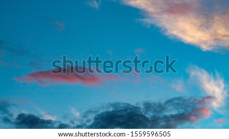 Colorful clouds at sunset with blue background.