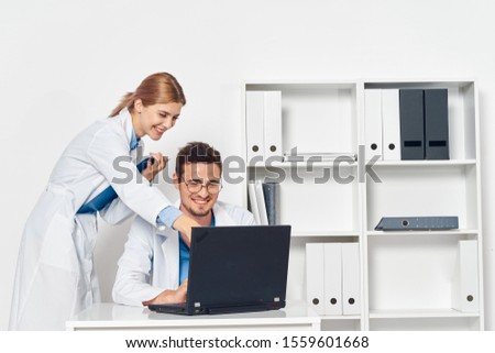 Woman shows man something in laptop at table interns medicine staff