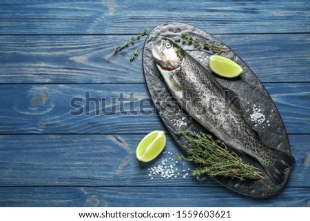 Raw cutthroat trout fish on blue wooden table, flat lay. Space for text