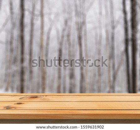 Wooden table top on winter sunny landscape with fir trees. Merry Christmas and happy New Year greeting background. Winter landscape with snow and christmas trees.Wooden table top on winter sunny lands