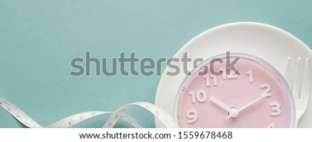 Pink clock on white plate, Intermittent fasting concept, ketogenic diet, weight loss, skip meal, new year 2020 diet and health resolution Royalty-Free Stock Photo #1559678468