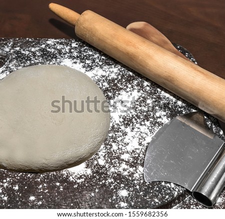 Raw  round pizza dough  on cutting board with rolling pin and cutter. Stock Image