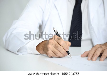 Doctor with white coat writing on papers